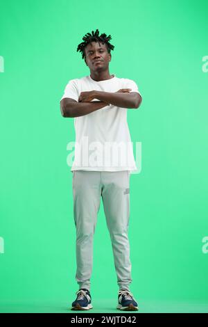 Un homme, plein pied, sur un fond vert, croisa les bras Banque D'Images