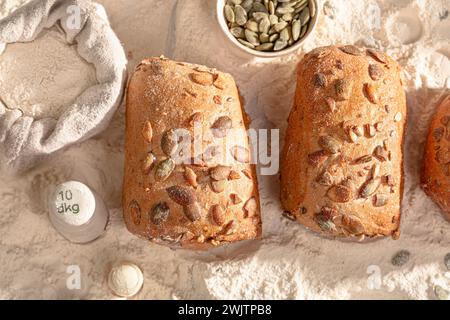 Rouleaux de citrouille dorée et ingrédients sur la table. Petits pains cuits dans une boulangerie. Banque D'Images
