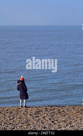 solitaire femme d'âge moyen debout sur la plage de galets regardant vers la mer, aldeburgh suffolk angleterre Banque D'Images