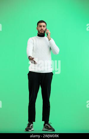 Un homme, pleine longueur, sur fond vert, parlant au téléphone Banque D'Images
