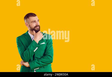 Homme en costume vert isolé sur fond jaune regardant l'espace de copie et pensant Banque D'Images