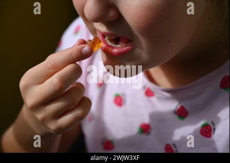 Jeune fille - enfant mangeant des bonbons et des bonbons. Détail du visage et de la bouche. Concept pour un mode de vie sain - sain - malsain nourriture sucrée et sucre. Banque D'Images