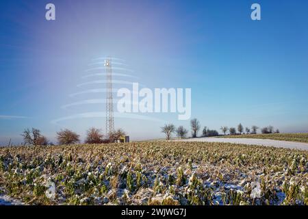 Antenne relais radio 5G sur champ enneigé. Le rayonnement est symbolisé par des objets transparents. Banque D'Images