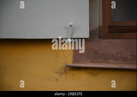 Fenêtre de maison rurale avec un volet en bois et un chien volet en métal contre un mur en stuc ocre à Turckheim, Alsace France. Banque D'Images