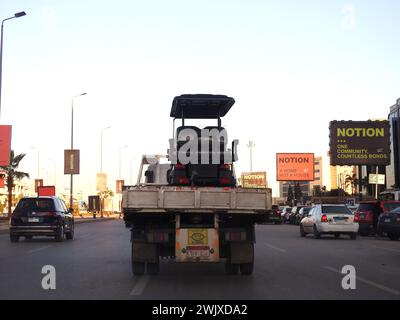 Le Caire, Égypte, 1er février 2024 : un camion à plateau hydraulique de transporteur de récupération de remorquage déplaçant un chariot de golf électrique se déplaçant dans la rue, un buggy de golf, un chariot ou Banque D'Images