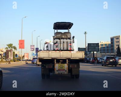 Le Caire, Égypte, 1er février 2024 : un camion à plateau hydraulique de transporteur de récupération de remorquage déplaçant un chariot de golf électrique se déplaçant dans la rue, un buggy de golf, un chariot ou Banque D'Images