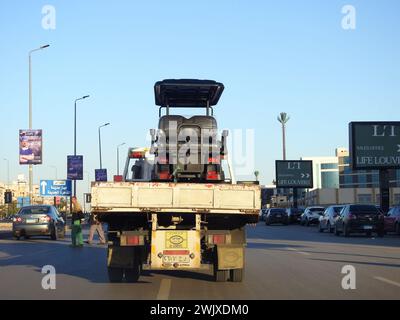 Le Caire, Égypte, 1er février 2024 : un camion à plateau hydraulique de transporteur de récupération de remorquage déplaçant un chariot de golf électrique se déplaçant dans la rue, un buggy de golf, un chariot ou Banque D'Images