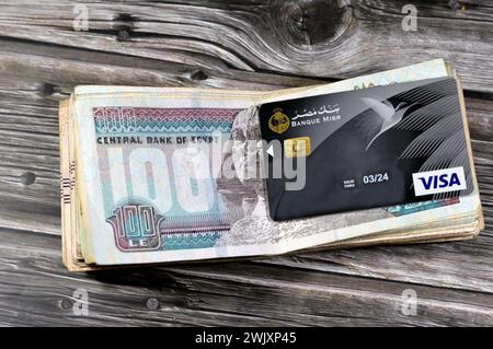 Le Caire, Egypte, 12 février 2024 : pile de billets de banque égyptiens de 100 cents livres et Banque Misr ou Egypte Banque carte VISA DE paiement électronique pour Banque D'Images