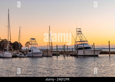 Coucher de soleil derrière des bateaux de pêche et des voiliers dans la marina sur Ward Cove au large de Rocky Bayou à Niceville, Floride Banque D'Images