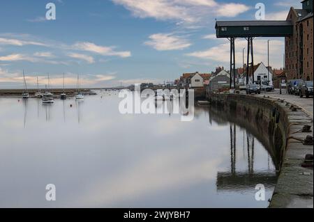 Wells-next-the-Sea, Norfolk, Angleterre, Royaume-Uni - bateaux à voile amarrés dans l'eau calme du port à marée haute. Bâtiment de grenier et ciel reflété dans l'eau Banque D'Images