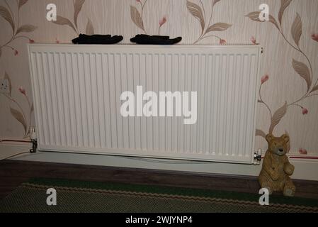 une paire de gants chauds d'hiver séchant sur un radiateur lors d'une crise du coût de la vie pour économiser de l'argent et de l'énergie Banque D'Images