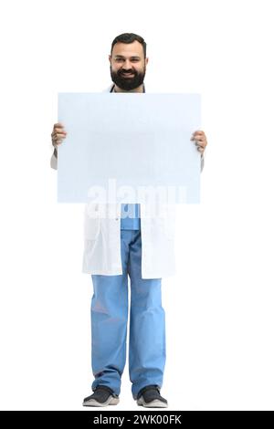 Un médecin masculin, pleine longueur, sur fond blanc, montre une feuille blanche Banque D'Images