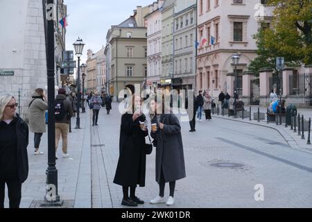 Deux femmes avec un café regardent un téléphone dans la rue Grodzka dans le vieux Cracovie, Pologne Banque D'Images