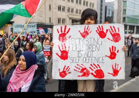 Leeds, Royaume-Uni. 17 FÉVRIER 2024. Un jeune enfant qui assiste à la manifestation pro-palestinienne sur la place de Leeds tient une pancarte avec des empreintes de mains ensanglantées et dit: "Bombarder des enfants n'est pas de l'autodéfense". Crédit Milo Chandler/Alamy Live News Banque D'Images