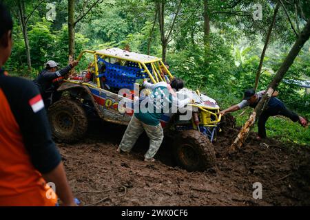 Le comité organisateur évacue une voiture hors route qui s’est écrasée sur une piste boueuse pendant la compétition de l’OIF à Kediri, Java oriental, Indonésie Banque D'Images