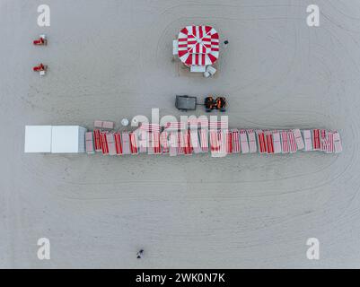 Vue aérienne de chaises de plage à rayures rouges blanches empilées sur South Beach Miami avec parasol rouge blanc Banque D'Images
