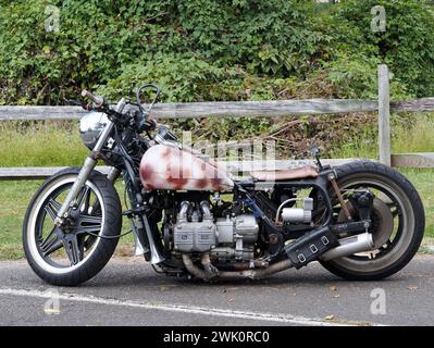 La moto est garée devant la clôture. Banque D'Images