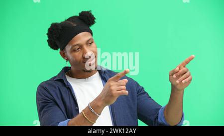 Un homme, gros plan, sur fond vert, pointe sur le côté Banque D'Images