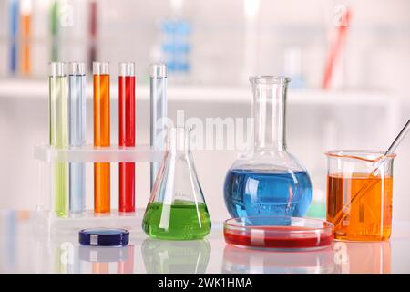 Analyse de laboratoire. Verrerie différente avec des liquides sur la table blanche sur fond flou Banque D'Images
