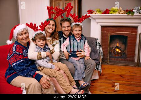 Noël, portrait et grande famille heureuse sur le canapé à la maison pour les vacances ou la célébration festive. Noël, parents et sourire des enfants avec grand-mère dans Banque D'Images