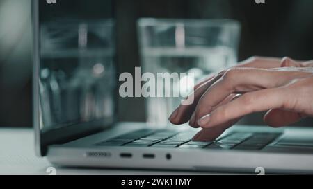 Gros plan de saisie sur ordinateur portable. Les mains de femme travaillant sur le projet en ligne, le rapport et la recherche au bureau. Planification, affaires, travailleuse écrivant des e-mails, productivité et occupé sur l'informatique. Vue latérale de la coloration bleue Banque D'Images