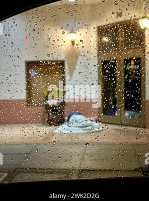 Santa Barbara, CA, États-Unis. 17 février 2024. Les premières pluies de la tempête imminente sur une fenêtre, avec un sans-abri dormant sur le trottoir et un chariot à l'arrière-plan dans le centre-ville de Santa Barbara le 17 février 2024. (Crédit image : © Amy Katz/ZUMA Press Wire) USAGE ÉDITORIAL SEULEMENT! Non destiné à UN USAGE commercial ! Banque D'Images