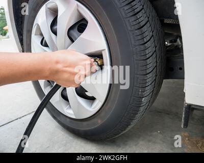 homme remplissant la pression d'air dans le pneu de voiture gros plan Banque D'Images