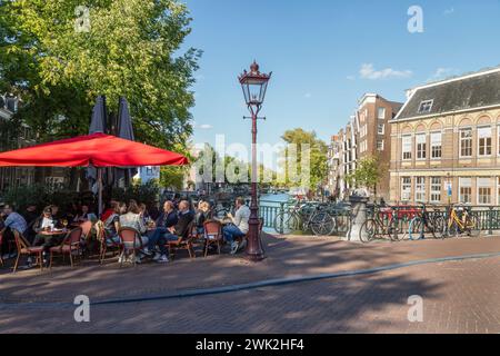 Les gens dans un endroit ombragé profitent de la terrasse près d'un pont dans le centre d'Amsterdam. Banque D'Images