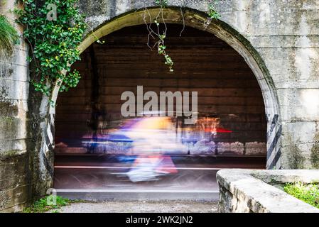 Cyclistes et voitures avec flou de mouvement dans un tunnel de la route panoramique Gardesana occidentale au-dessus de Limone, Lombardie, Italie Banque D'Images