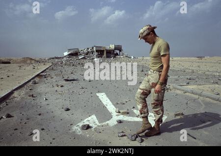 Première guerre du Golfe : 15 mars 1991. Un soldat de la coalition examine les débris près d'un poste de péage bombardé sur le pont menant à l'île de Bubiyan, dans le nord-est du Koweït. Banque D'Images