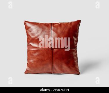 Coussin de canapé carré décoratif fait de patchs soigneusement cousus de cuir lisse de couleur cuivre véritable rempli de mousse isolé sur fond blanc Banque D'Images