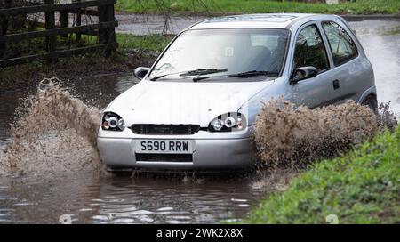 Eton, Windsor, Royaume-Uni. 18 février 2024. Automobilistes conduisant à travers les eaux de crue sur un pays à Eton, Windsor, Berkshire après de fortes pluies nocturnes. Crédit : Maureen McLean/Alamy Live News Banque D'Images