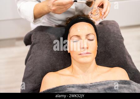 Cosmétologue sans visage faisant le traitement du visage à la femme en salon Banque D'Images