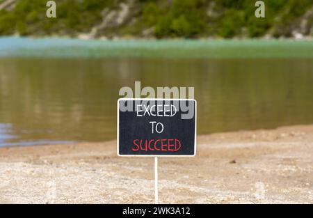 Symbole dépasser pour réussir. Les mots conceptuels dépassent pour réussir sur un beau tableau noir de craie noire. Beau fond de lac de montagne. Business et Excess Banque D'Images