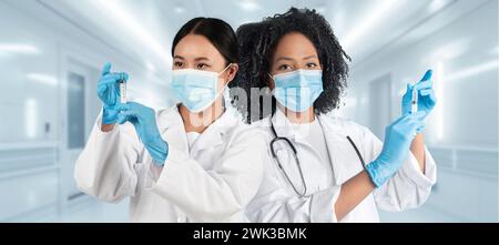 Deux travailleuses de la santé diverses en manteaux blancs et gants bleus Banque D'Images