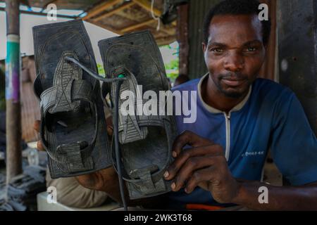 Dar es Salaam, Tanzanie. 16 février 2024. Patrick Yoram Sudae montre des sandales localement connues sous le nom de 'Katambuga' fabriquées à partir de pneus recyclés dans un atelier de rue à Dar es Salaam, Tanzanie, le 16 février 2024. Crédit : Herman Emmanuel/Xinhua/Alamy Live News Banque D'Images