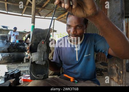 Dar es Salaam, Tanzanie. 16 février 2024. Patrick Yoram Sudae fabrique des sandales localement connues sous le nom de 'Katambuga' fabriquées à partir de pneus recyclés dans un atelier de rue à Dar es Salaam, Tanzanie, le 16 février 2024. Crédit : Herman Emmanuel/Xinhua/Alamy Live News Banque D'Images