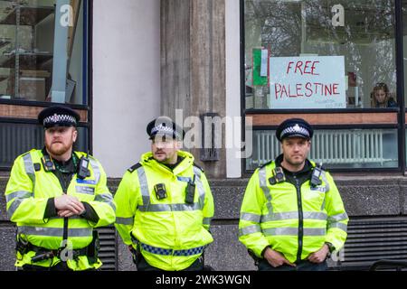 Londres, Royaume-Uni. 17 février 2024. Des policiers se tiennent devant une pancarte indiquant « Palestine libre » dans la fenêtre d'un bureau le long de la route de dizaines de milliers de manifestants pro-palestiniens participant à une Journée mondiale d'action pour appeler à un cessez-le-feu immédiat et permanent à Gaza. Les manifestants ont défilé vers l'ambassade israélienne pour la première fois depuis le 7 octobre 2023. Crédit : Mark Kerrison/Alamy Live News Banque D'Images