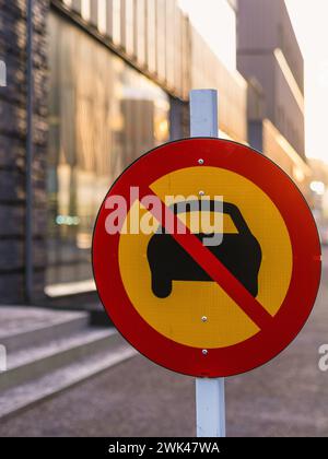 Un panneau d'interdiction d'entrée bien visible pour les véhicules est clairement affiché sur un poteau métallique le long d'une rue urbaine. Le signe circulaire sur fond rouge et jaune Banque D'Images