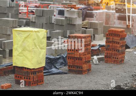 Briques rouges et blocs de béton livrés sur le chantier et placés à côté du lieu de travail prêt pour les briques Banque D'Images