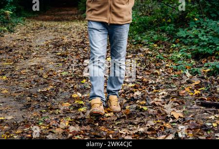Randonnée d'automne à travers l'herbe haute dans le bois. Gros plan de marche dans la forêt Banque D'Images