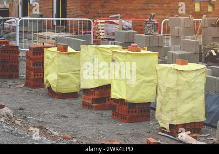 Briques rouges et blocs de béton livrés sur le chantier et placés à côté du lieu de travail prêt pour les briques Banque D'Images