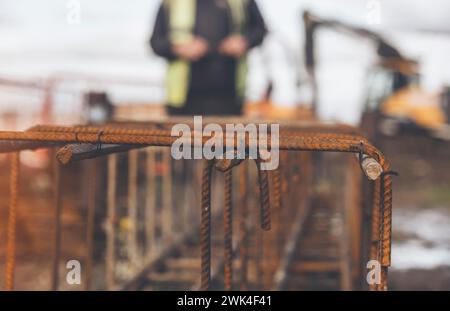 Un travailleur utilise du fil de liage en acier pour attacher des tiges d'acier aux barres de renfort en gros plan. Structures en béton armé - fabrication d'une cage d'armature en acier f Banque D'Images