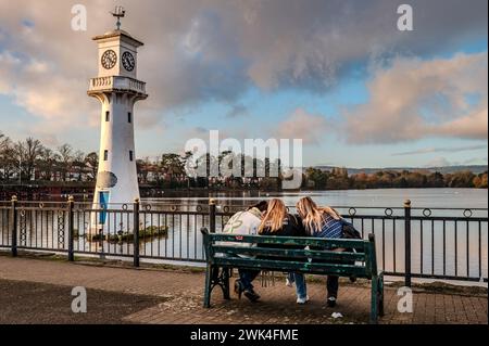 Roath Park Lake à Cardiff. Le phare Scott Memorial est en mémoire du capitaine Scott qui est parti de Cardiff pour son expédition polaire. Trois filles. Banque D'Images