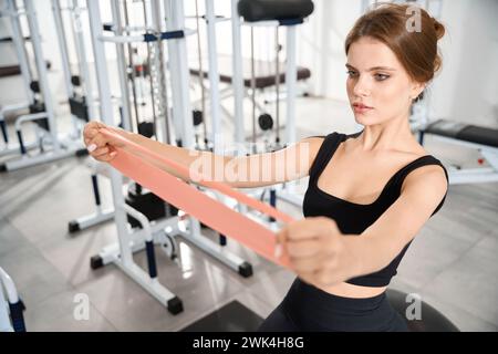 Femme effectue des exercices avec une bande élastique de fitness Banque D'Images