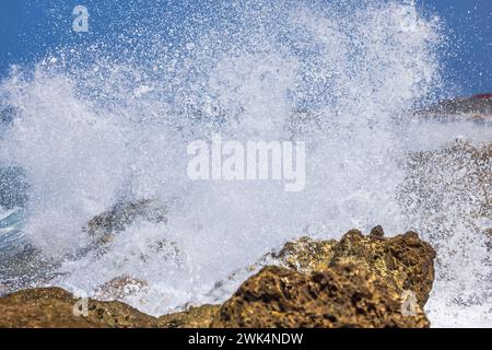 Vue rapprochée des éclaboussures de vagues s'écrasant contre les rochers dans la mer des Caraïbes. Curaçao. Banque D'Images