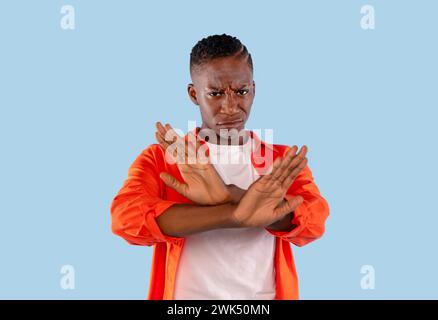 femme en chemise orange croisant les mains et les paumes dans le refus réaction d'expression négative sur fond bleu. Expression humaine négative et langage corporel Banque D'Images