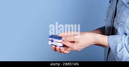 Test automatique des taux d'oxygène sanguin effectué par la femme à partir de l'oxymètre de pouls Banque D'Images