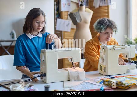 Portrait de deux jeunes filles handicapées utilisant des machines à coudre à l'école ou en classe de formation professionnelle Banque D'Images