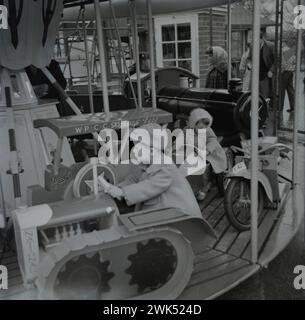 Enfants sur un carrousel de foire (rond-point, carrousel) au début des années 1960 Cette image a été prise à partir de la diapositive originale donc il y a peut-être des imperfections. Banque D'Images